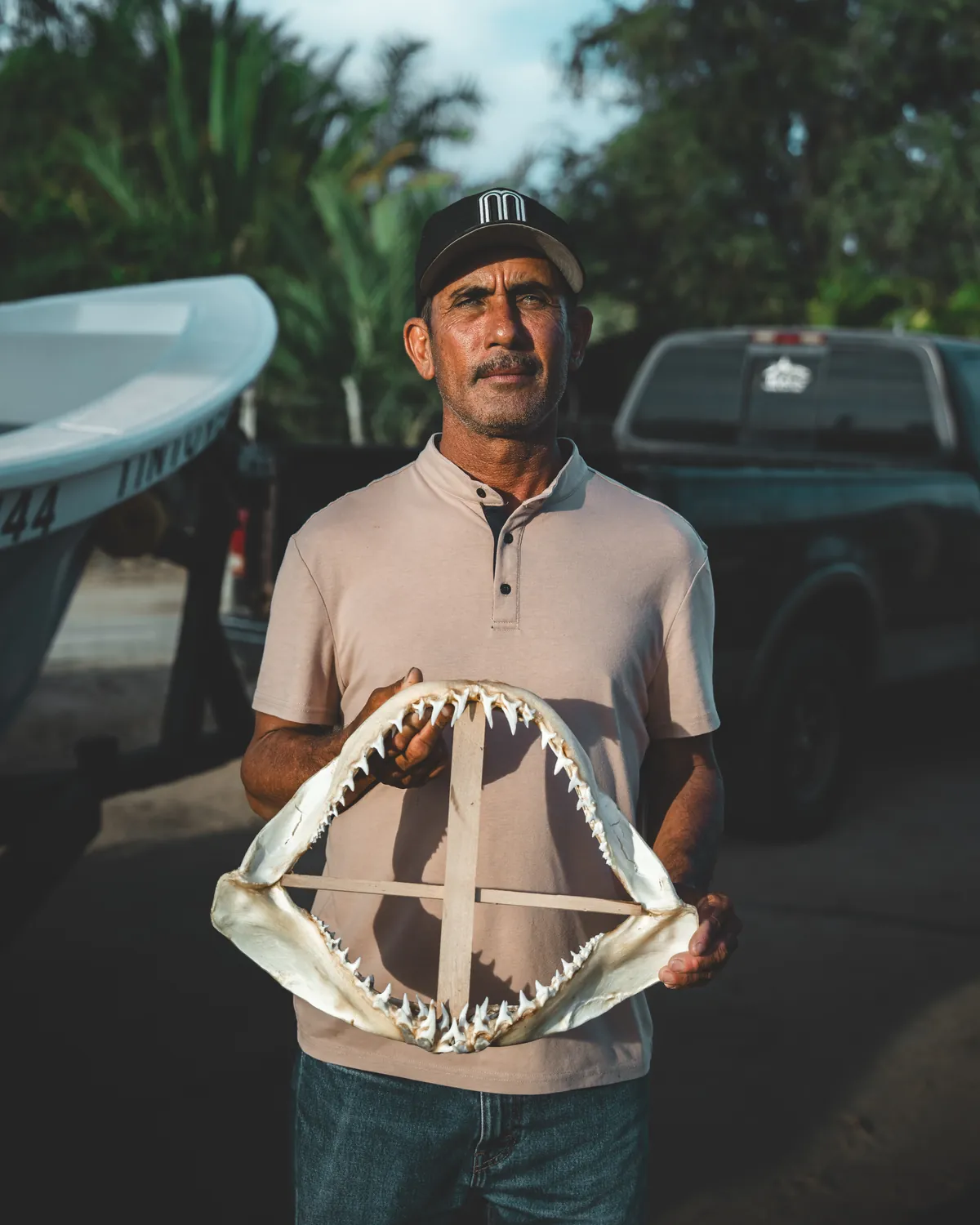 Pescador sosteniendo una mandíbula de tiburón frente a su panga